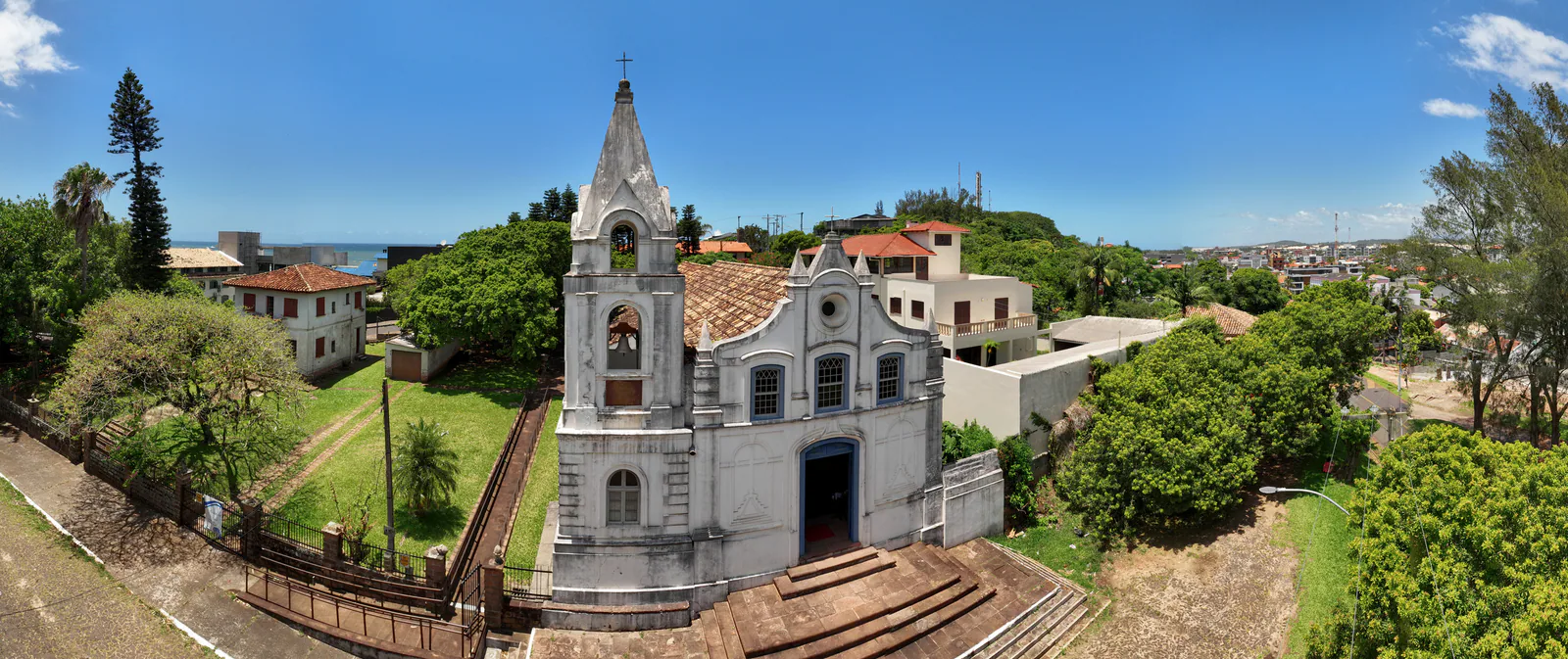 Vista aérea de la fachada de la Igreja Matriz São Domingos, con torre, escalinata y árboles alrededor