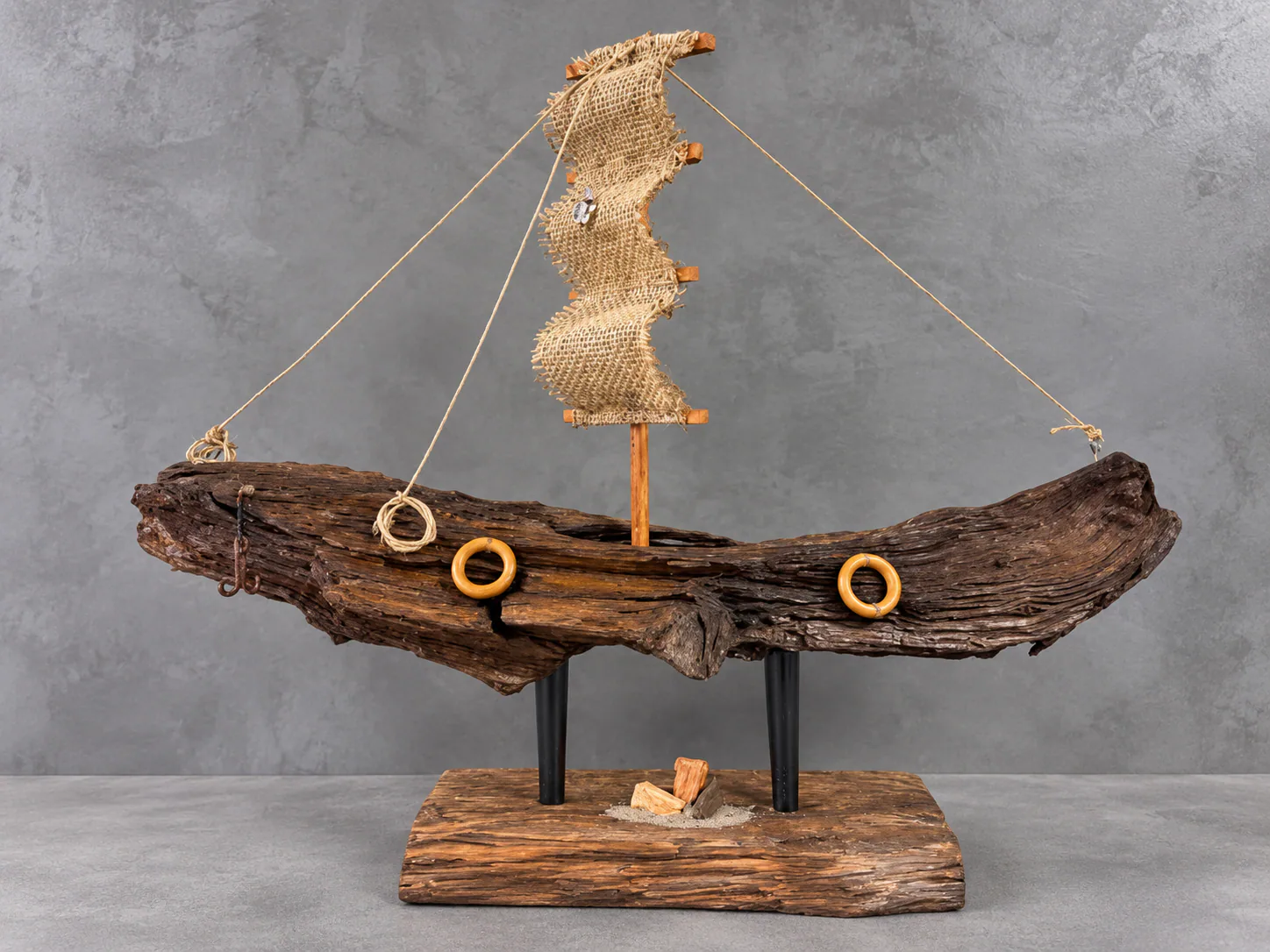 Barco artesanal de madeira com vela de juta e base rústica
