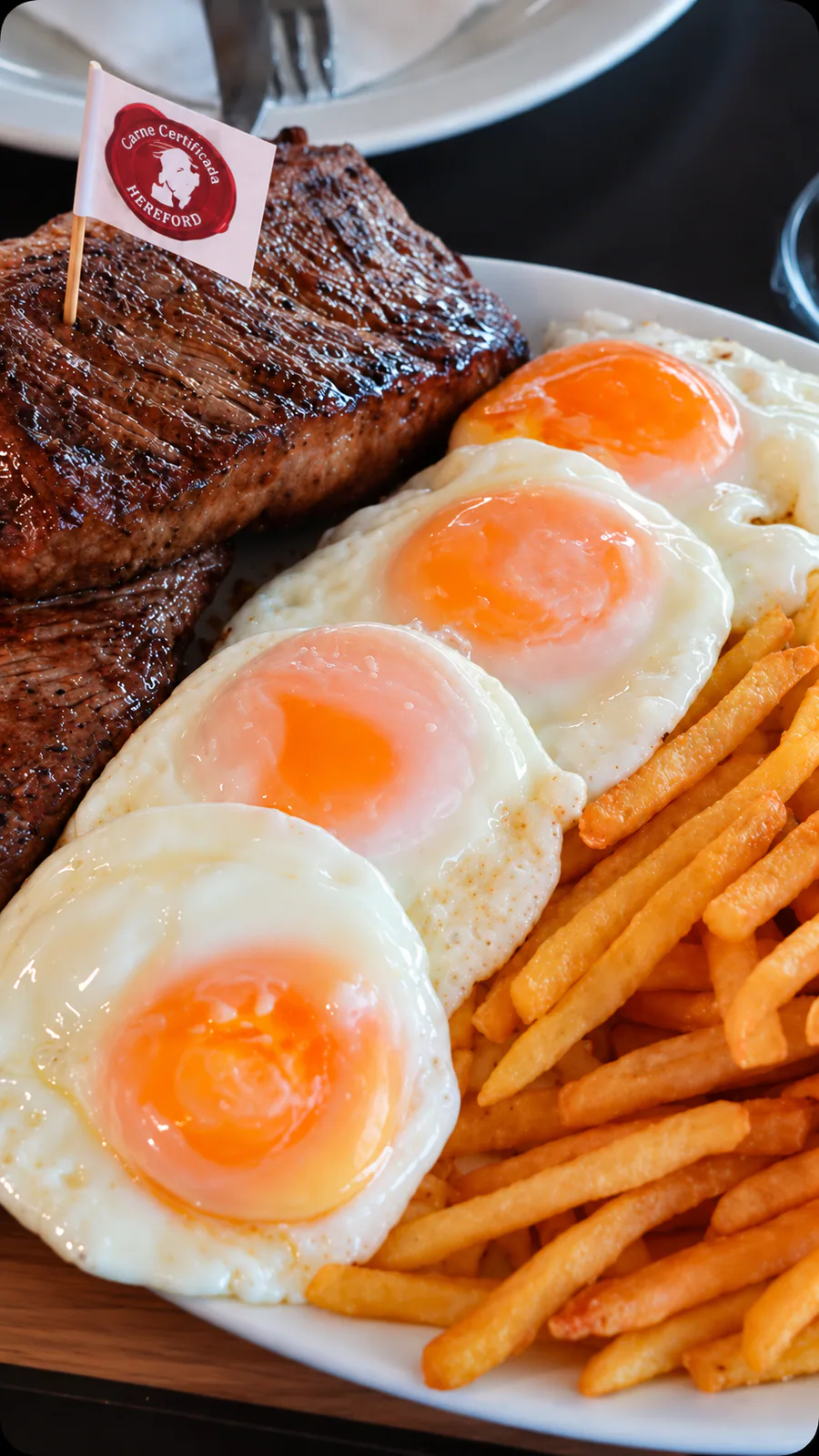 Carne grelhada acompanhada de quatro ovos fritos e batatas fritas