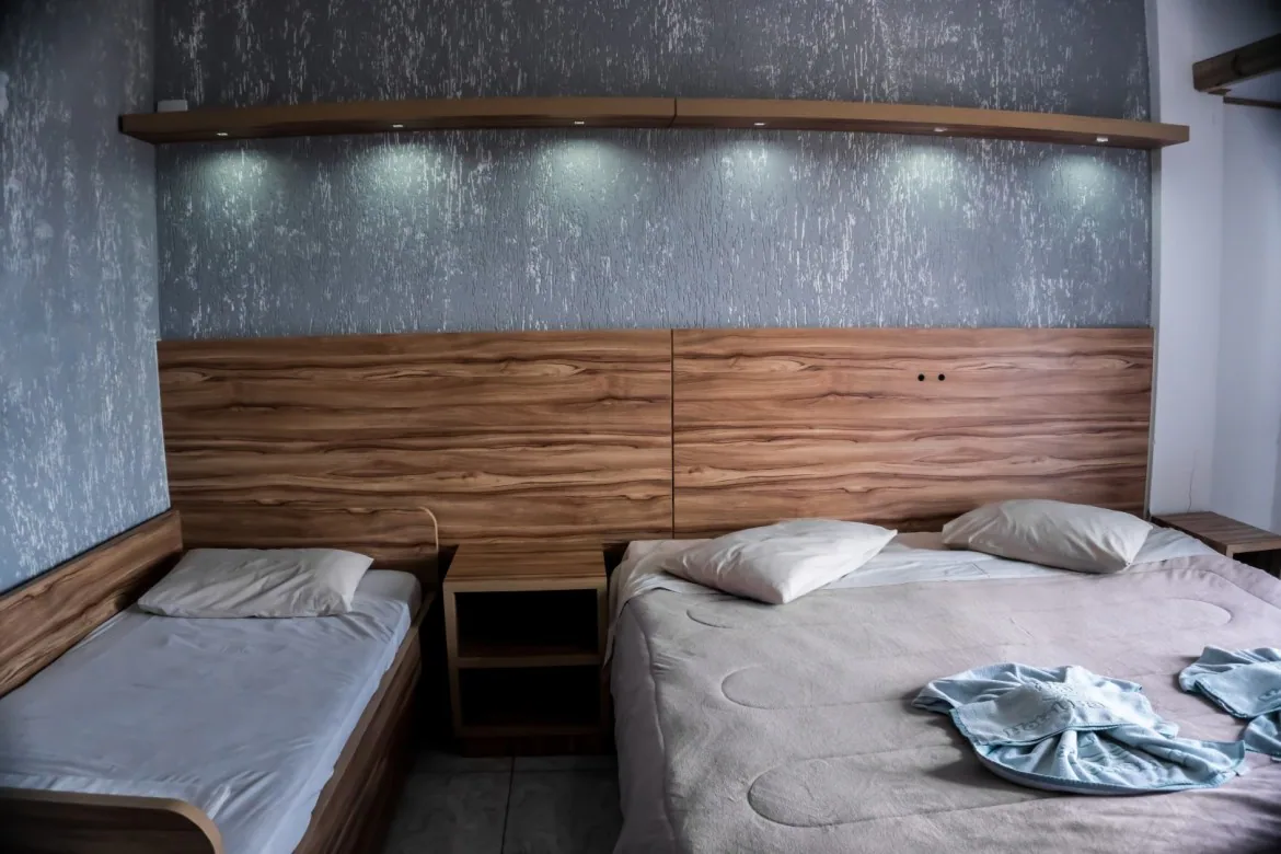 Quarto do Hotel Bauer com cama de casal, cama de solteiro e cabeceira de madeira