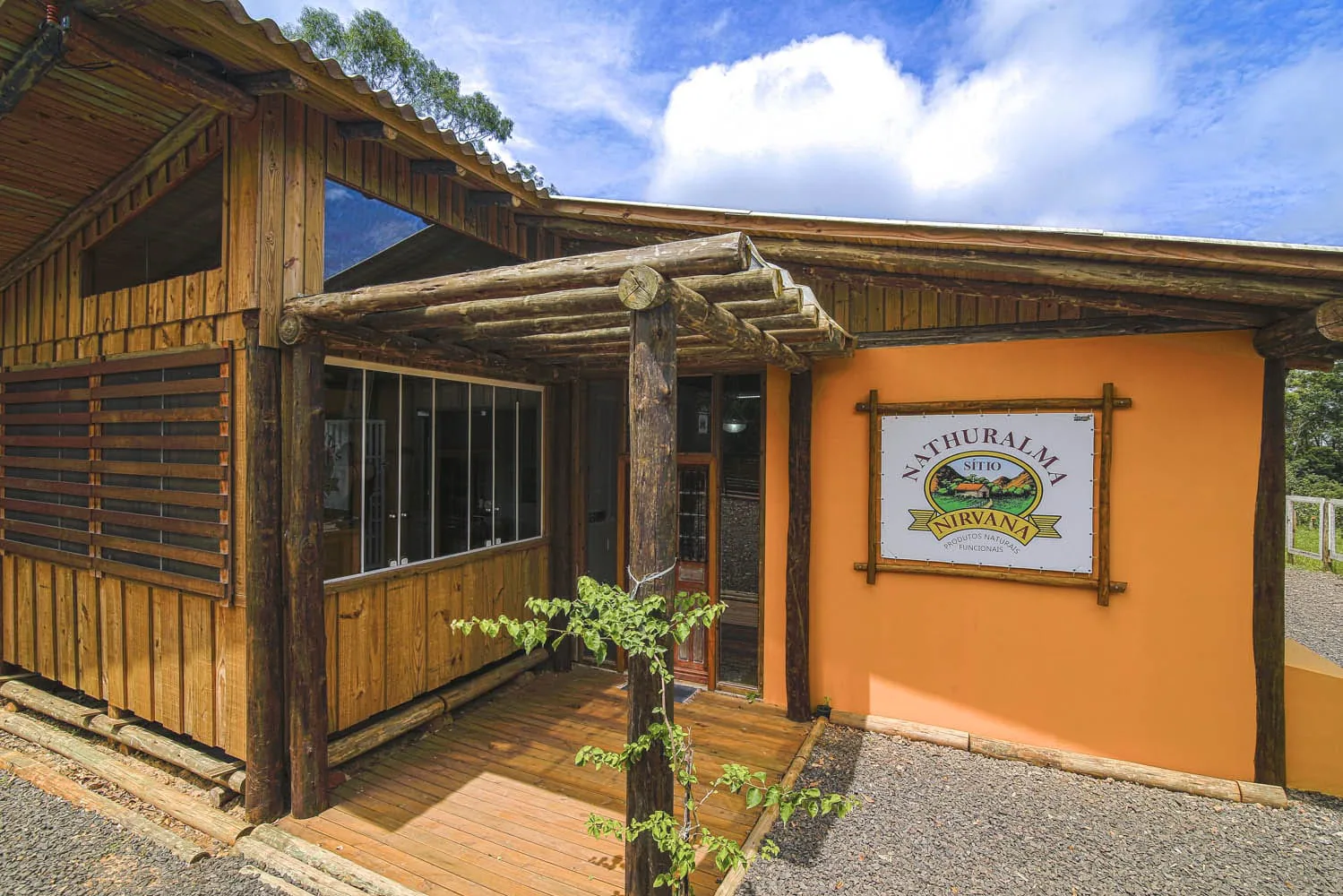 Entrada de madeira e fachada amarela do Sítio Nirvana