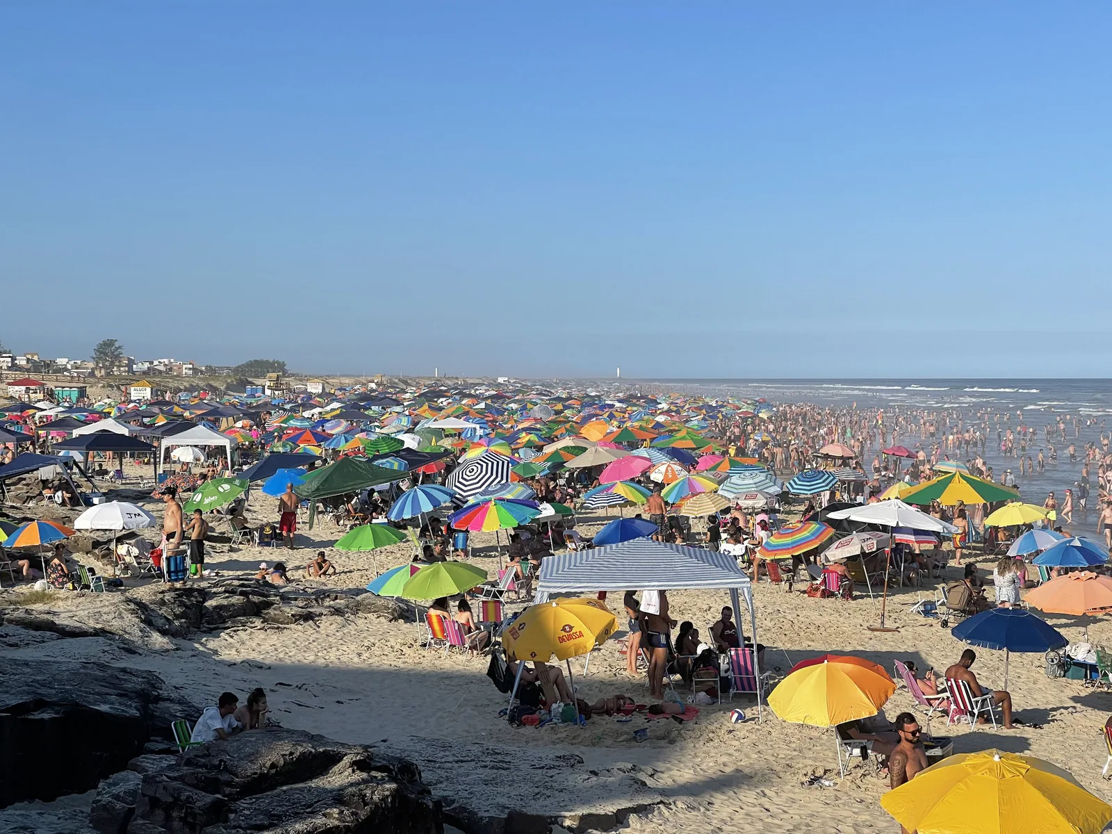 Praia Grande com muitos banhistas e guarda-sóis coloridos ao longo da areia