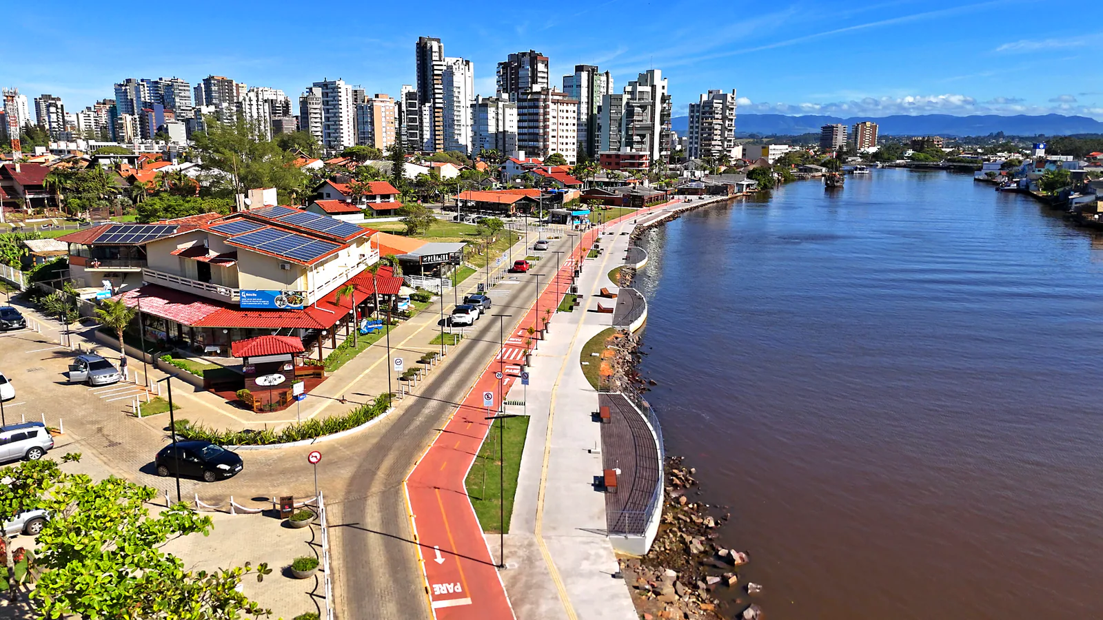 Vista da orla com decks, bancos e restaurantes ao longo do Rio Mampituba