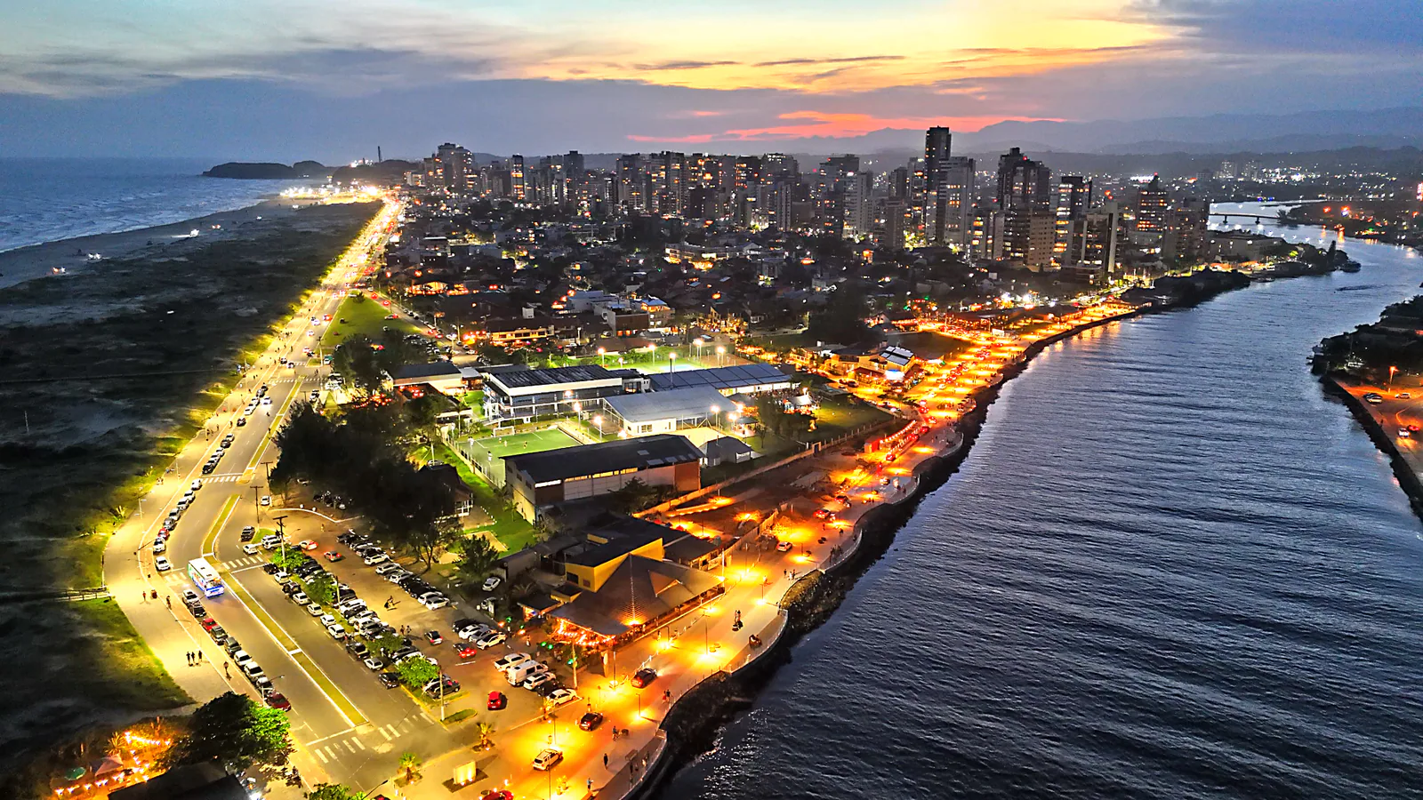 Orla Gastronômica e cidade iluminadas junto ao Rio Mampituba ao anoitecer