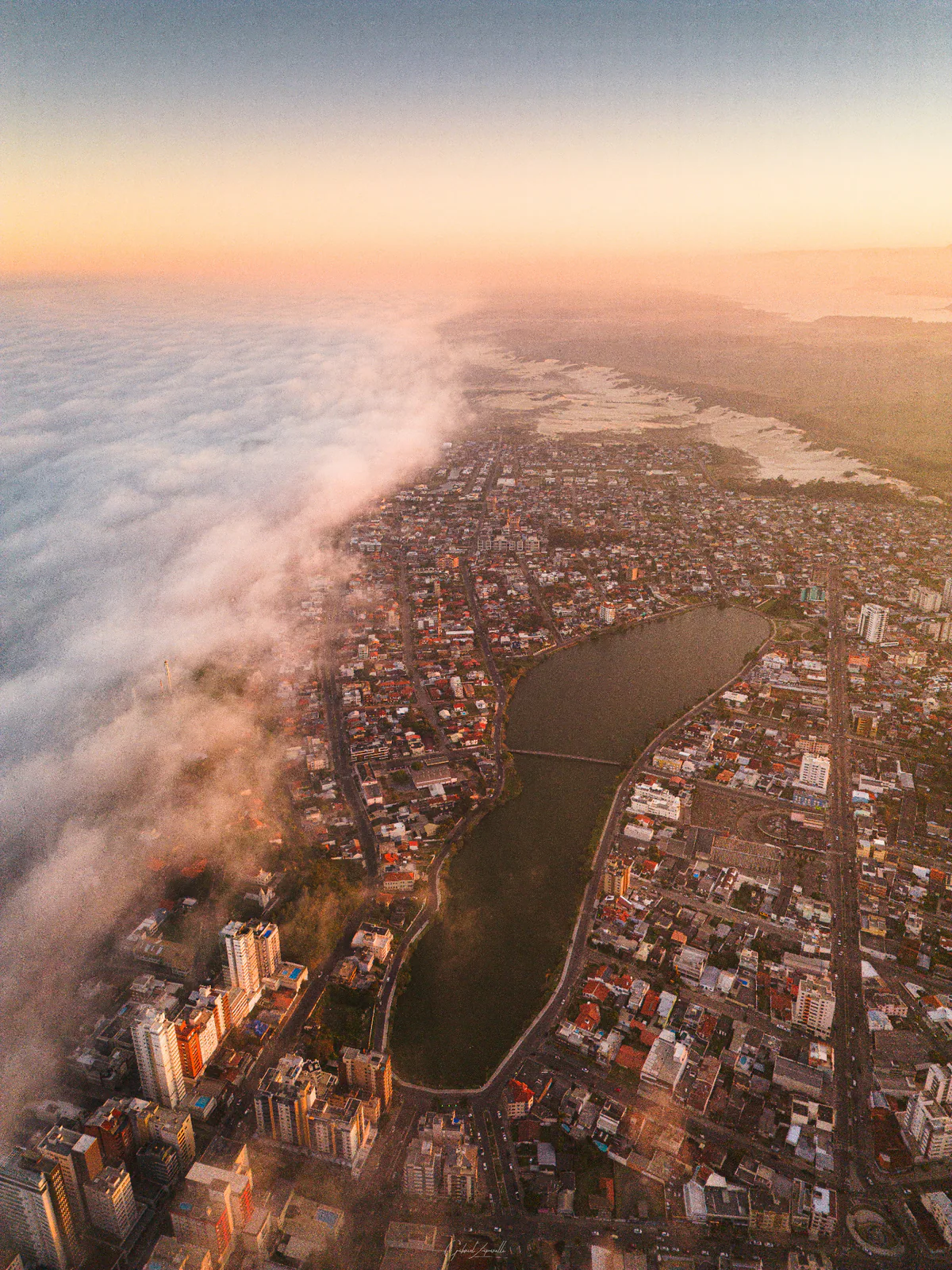 Aerial view of Lagoa do Violão and the urban area of Torres, with a band of clouds over the waterfront