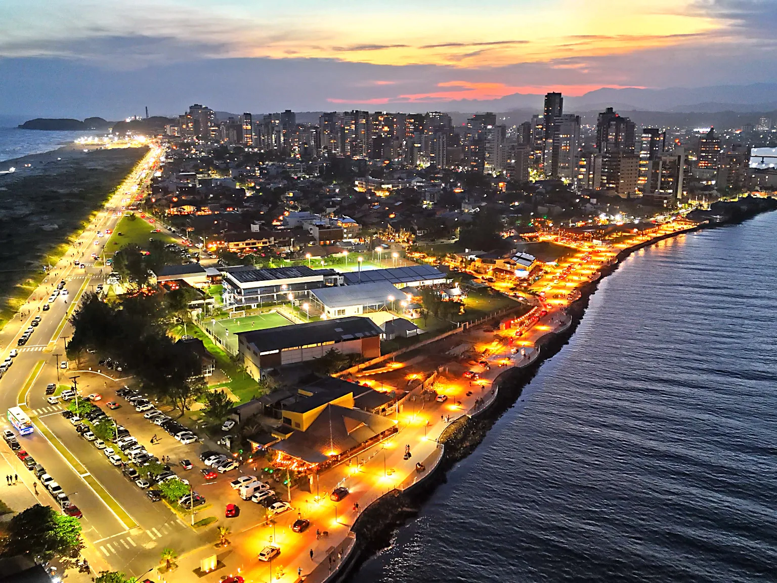 Orla Gastronômica e cidade iluminadas junto ao Rio Mampituba ao anoitecer