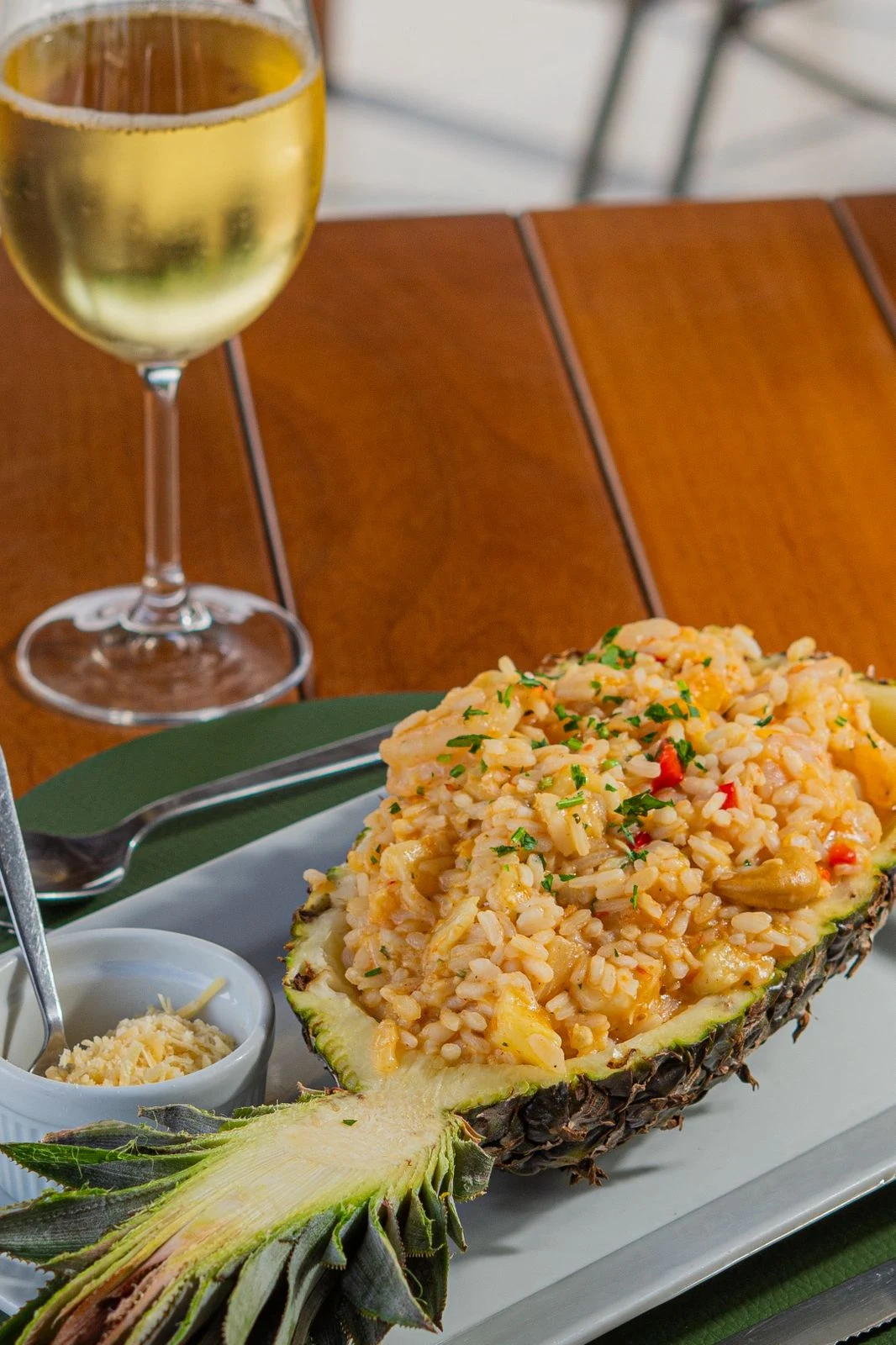 Arroz servido em metade de abacaxi com taça de vinho