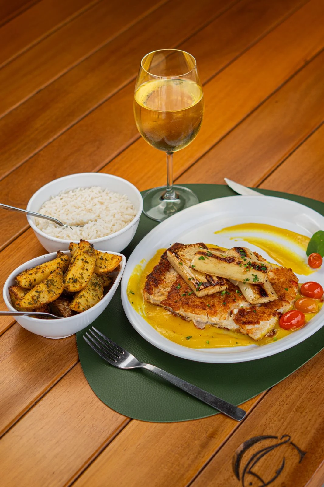Peixe com molho, arroz, batatas e taça de vinho