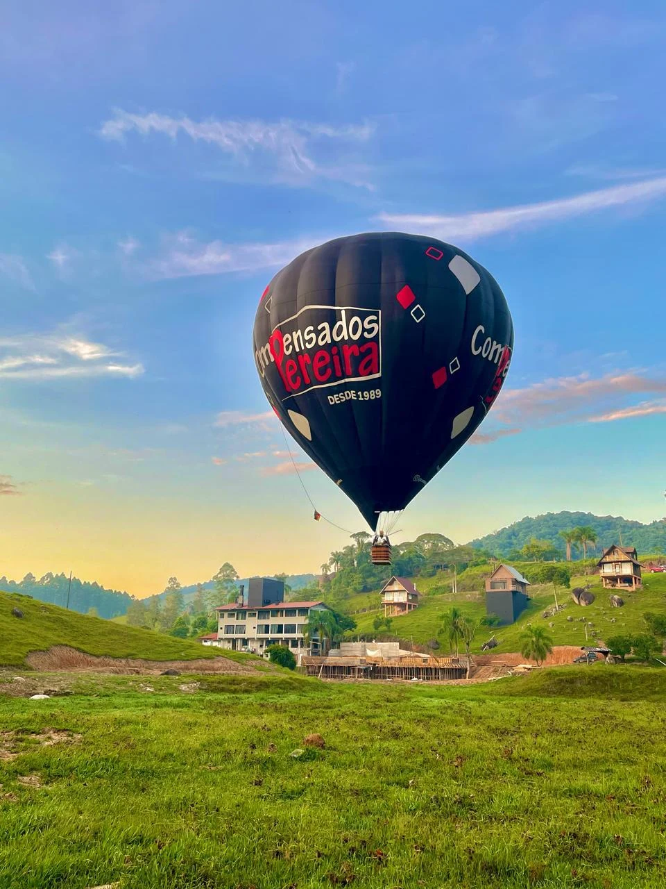 Balão em voo sobre uma área com gramado e construções