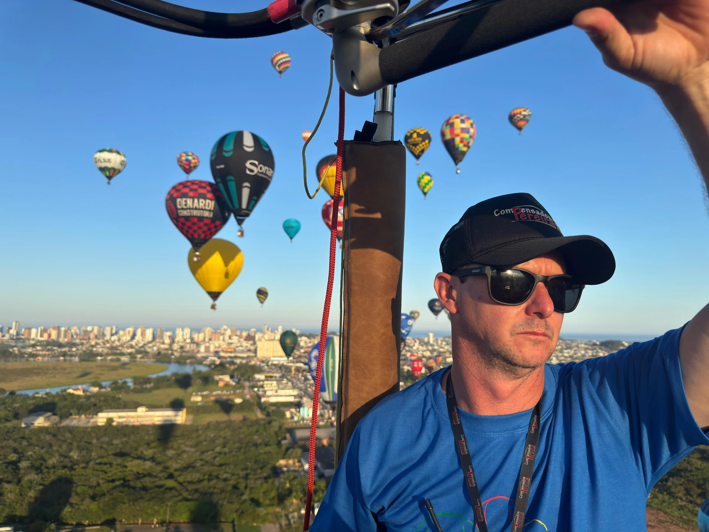 Piloto no cesto de um balão com outros balões ao fundo