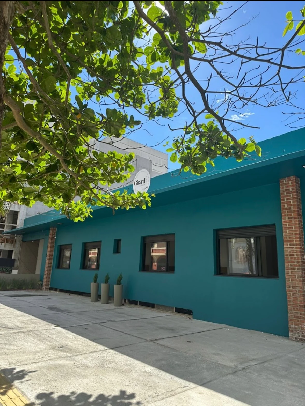 Fachada da Pousada Girardi, com paredes azul-petróleo e árvore em frente.