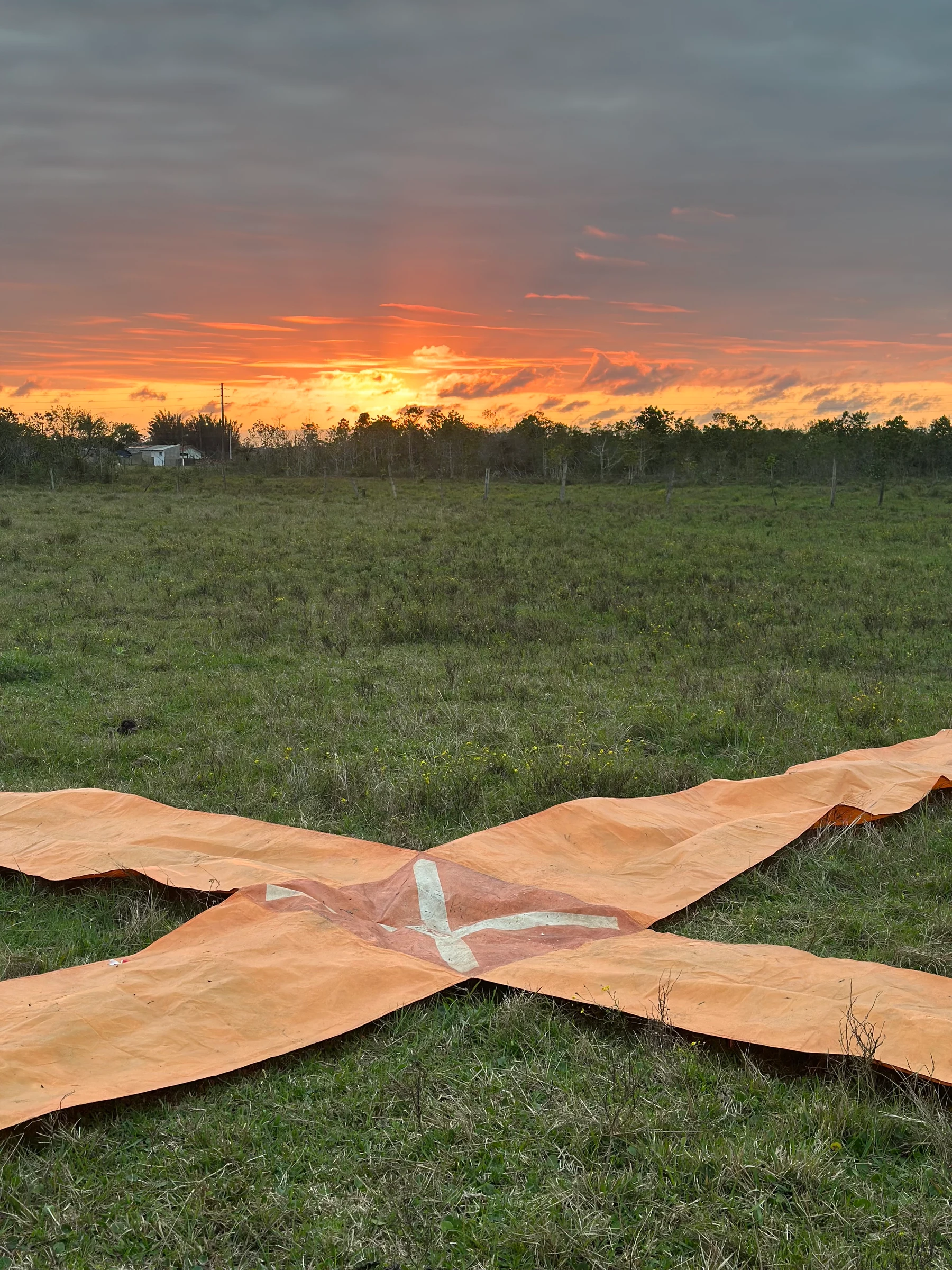 Alvo de tecido em formato de cruz sobre o gramado ao pôr do sol