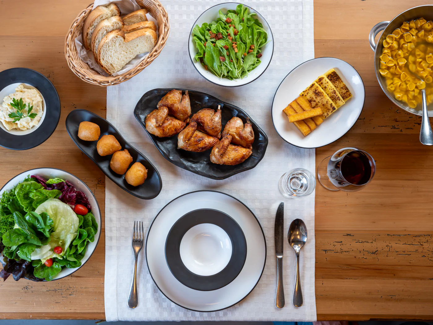Mesa com galeto, massas, saladas, pães e acompanhamentos